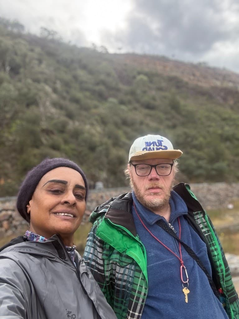 Two people out together on a walk with green hills behind them